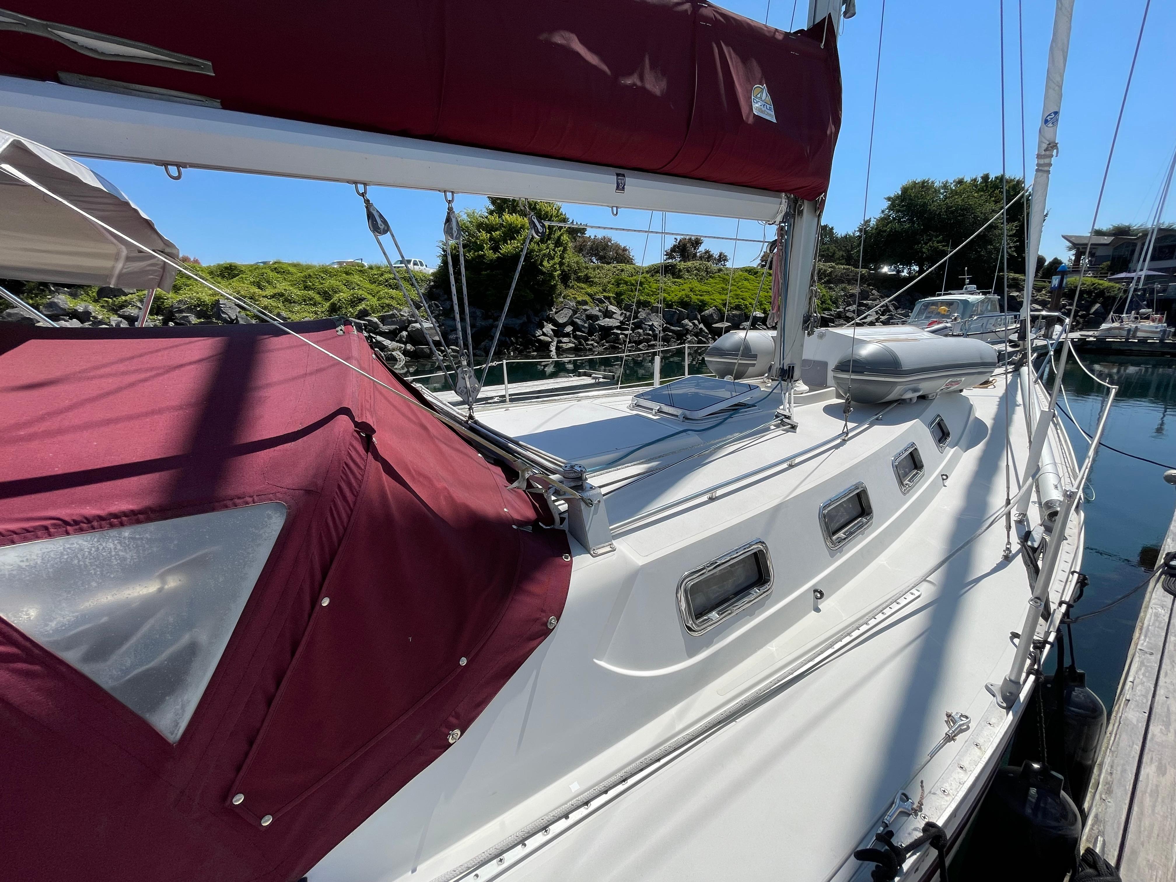 1980 CS 36 Traditional sailboat docked, featuring maroon canopy and sleek white deck.