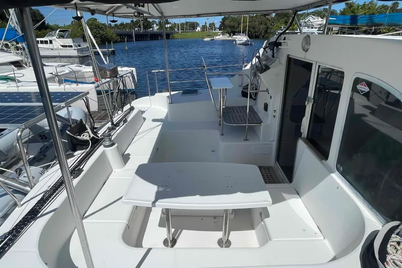 Acushla Yacht Photos Pics 2003 Lagoon 410-S2 catamaran deck with seating and table, docked by the water.