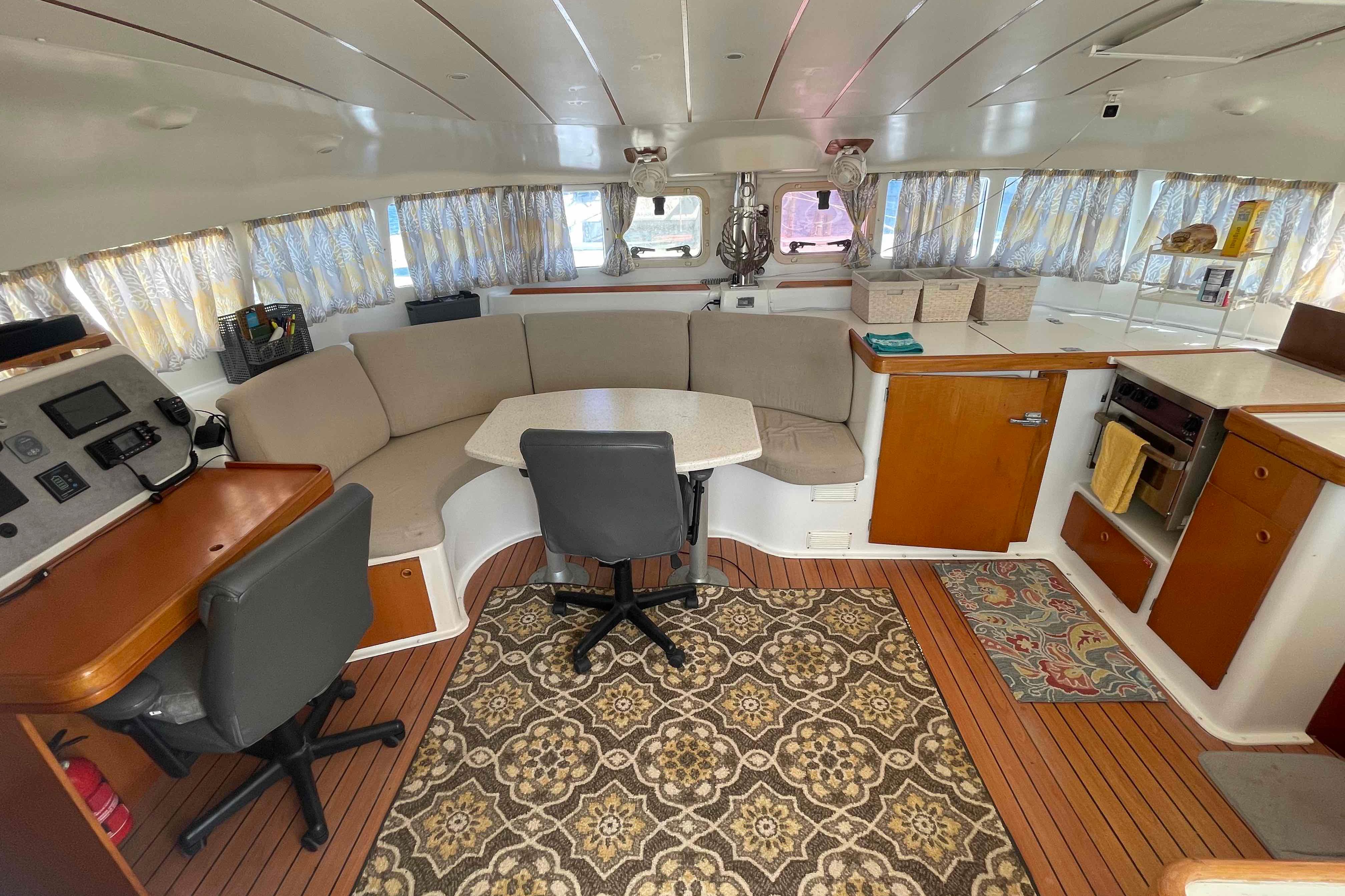 Interior of 2003 Lagoon 410-S2 catamaran with cozy seating, navigation station, and kitchen area.