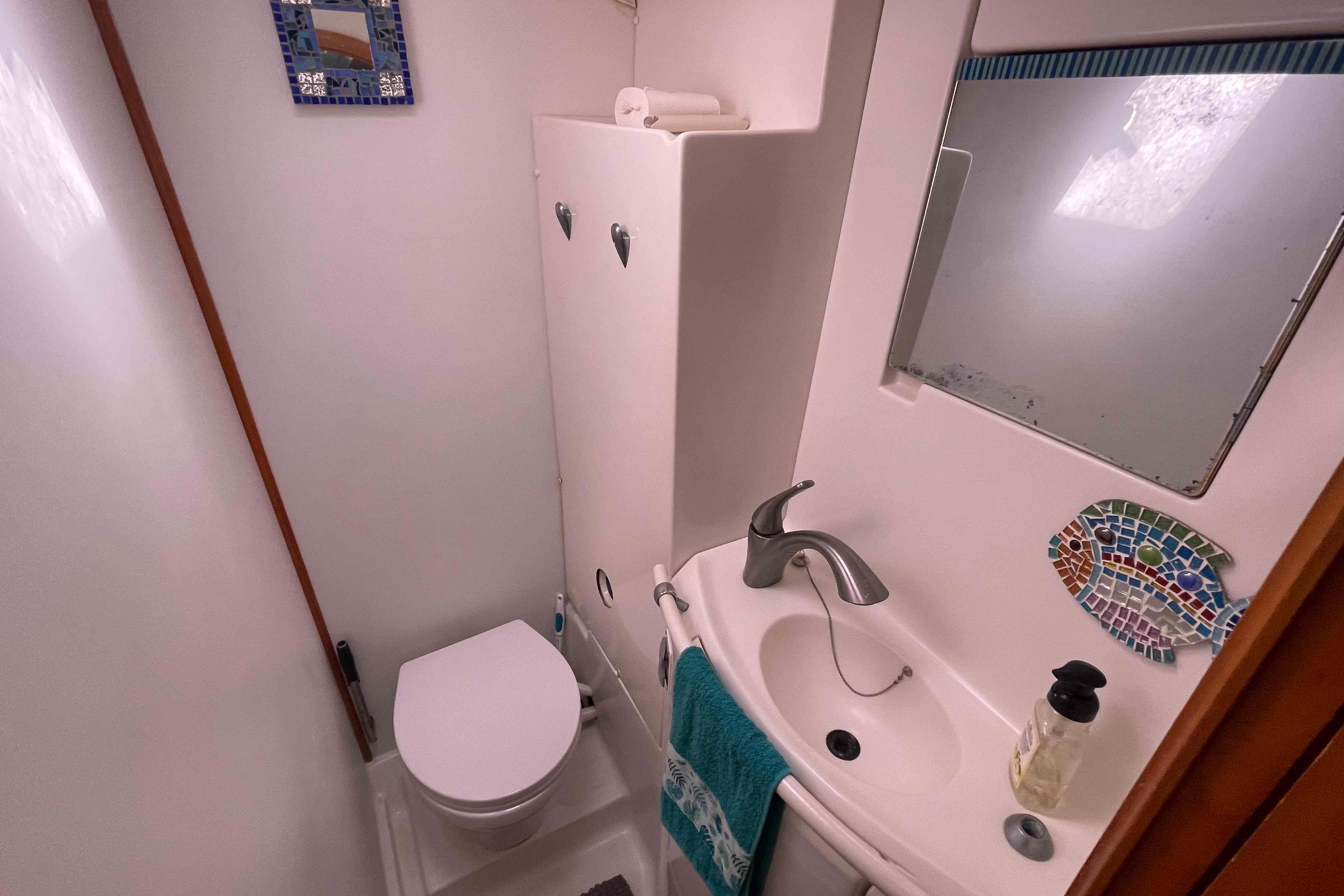 Compact bathroom in a 2003 Lagoon 410-S2 yacht with sink, toilet, and mirror.
