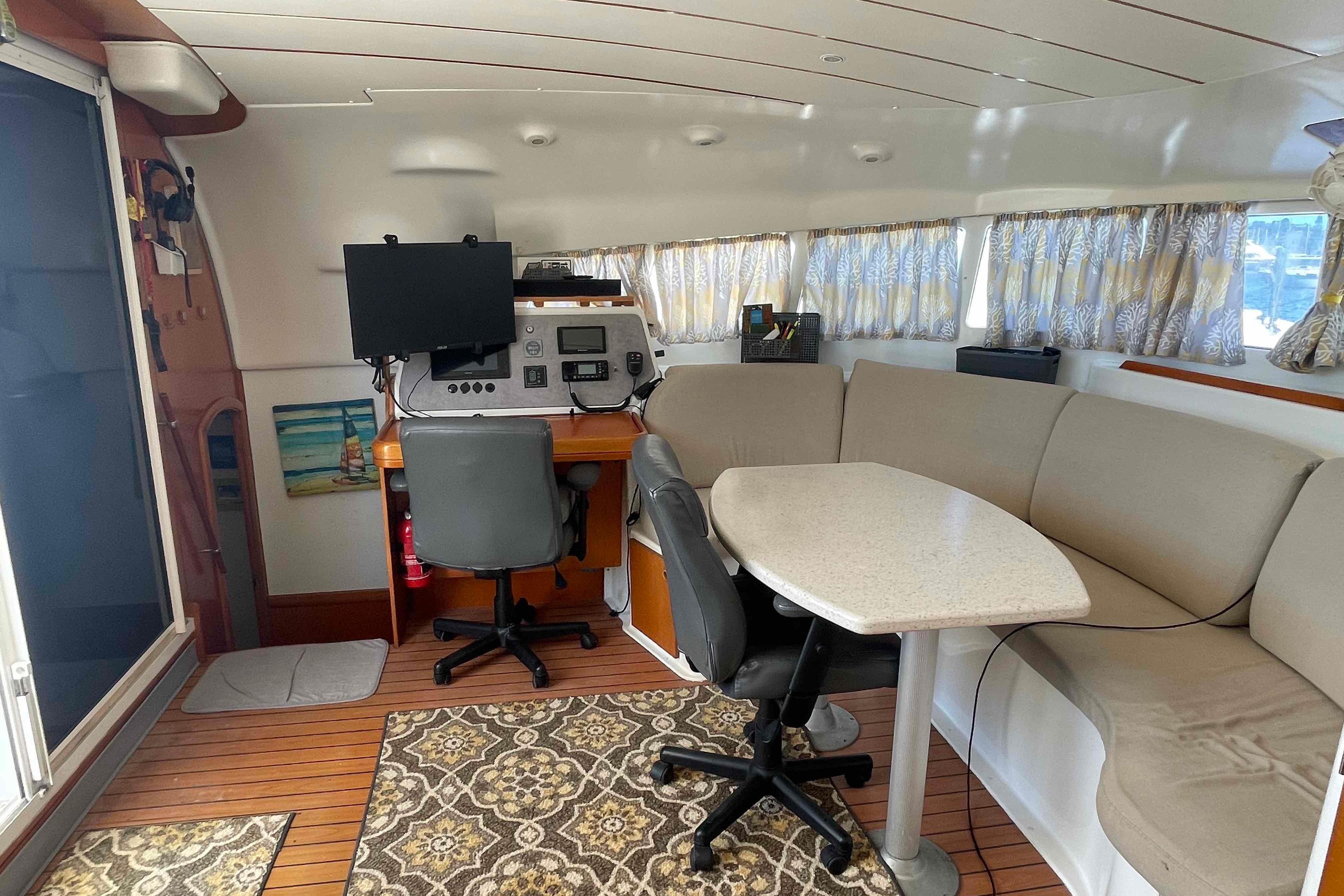 Interior of 2003 Lagoon 410-S2 catamaran with seating, table, and navigation station.