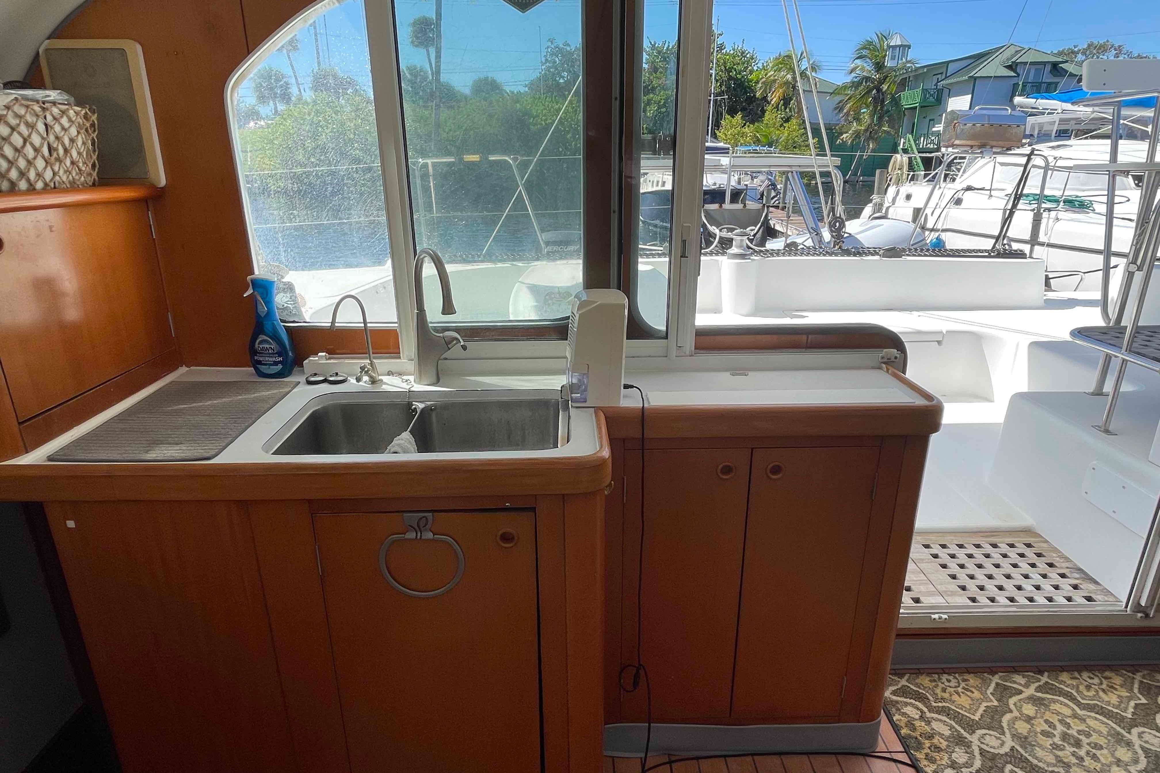 Interior view of 2003 Lagoon 410-S2 yacht kitchen with sink and outdoor access.