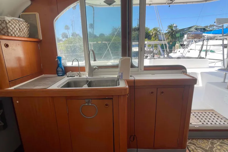 Acushla Yacht Photos Pics Lagoon 410-S2 2003 yacht kitchen with wooden cabinets and sink, marina view.