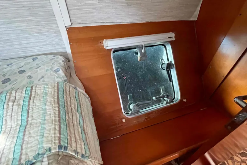 Acushla Yacht Photos Pics Interior of a 2003 Lagoon 410-S2 yacht cabin with a window and bedding.