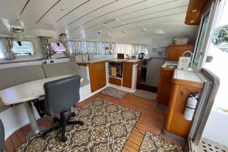 Acushla Yacht Photos Pics Interior of 2003 Lagoon 410-S2 catamaran with cozy seating, kitchen, and wooden flooring.
