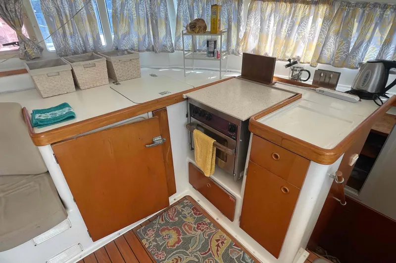 Acushla Yacht Photos Pics Interior of 2003 Lagoon 410-S2 yacht kitchen with stove, storage, and colorful curtains.