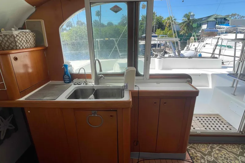 Acushla Yacht Photos Pics Interior view of 2003 Lagoon 410-S2 catamaran kitchen with sink and outdoor access.