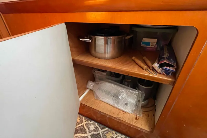 Acushla Yacht Photos Pics Open cabinet in 2003 Lagoon 410-S2 yacht with kitchen utensils and cookware.