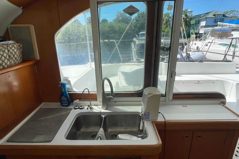Acushla Yacht Photos Pics Interior view of a 2003 Lagoon 410-S2 catamaran kitchen with sink and window.
