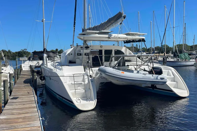 Acushla Yacht Photos Pics 2003 Lagoon 410-S2 catamaran docked at marina with inflatable boat attached.