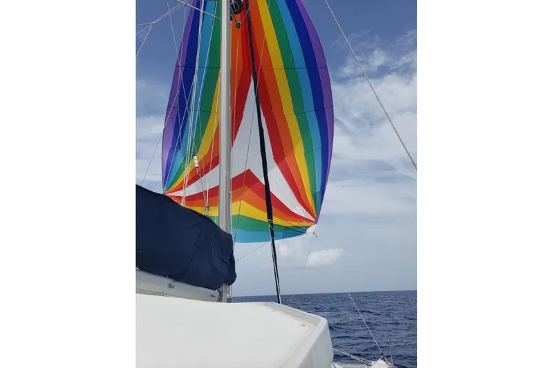 Acushla Yacht Photos Pics Colorful sail on 2003 Lagoon 410-S2 catamaran against blue sky and ocean backdrop.