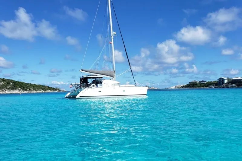 Acushla Yacht Photos Pics Sailing catamaran Lagoon 410-S2, 2003 model, on clear turquoise water under blue sky.