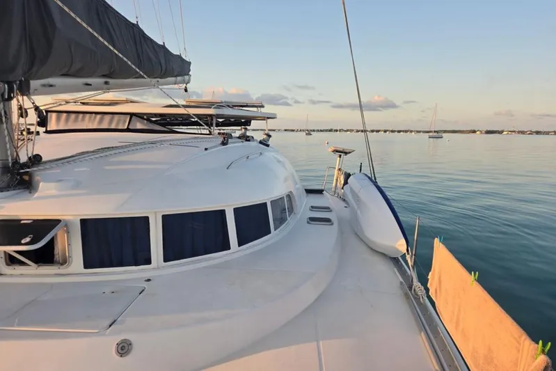 Acushla Yacht Photos Pics 2003 Lagoon 410-S2 catamaran on calm water at sunset, featuring sleek design and spacious deck.