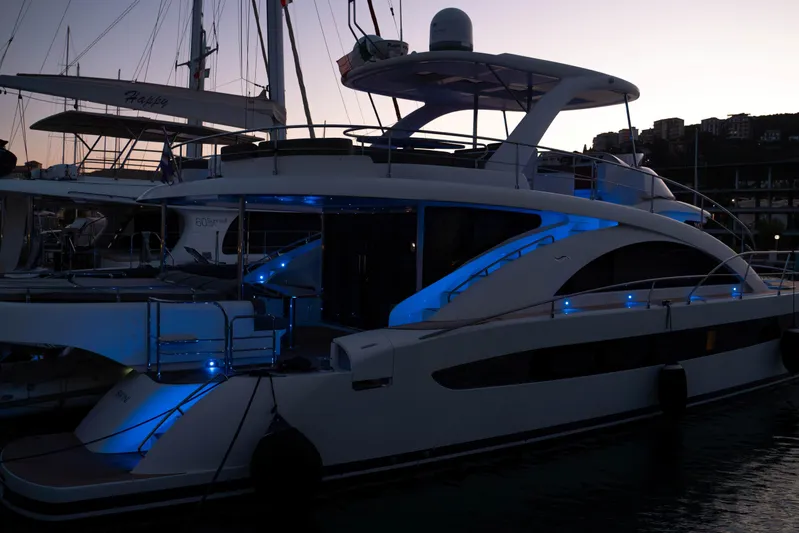 013 Yacht Photos Pics Luxurious VG 62 yacht from 2008 docked at sunset, illuminated with blue lights.