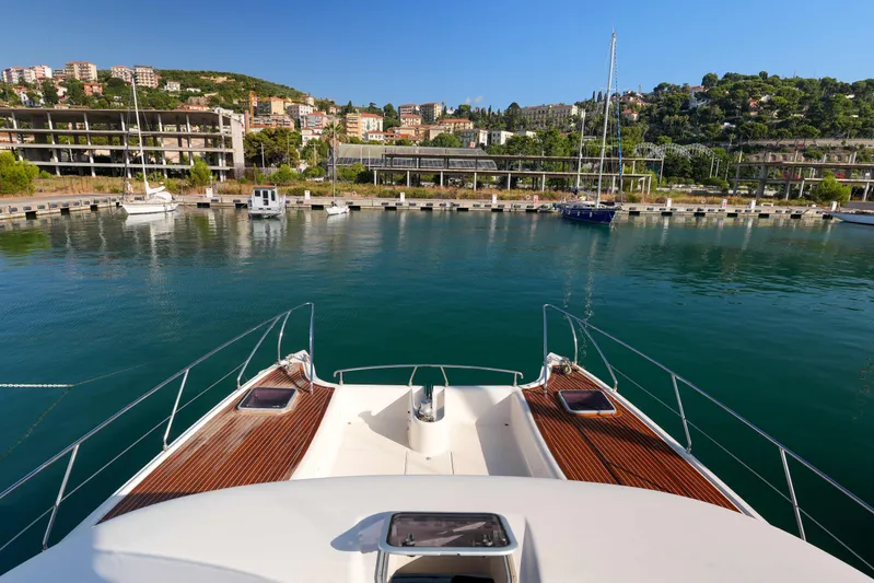 013 Yacht Photos Pics Bow view of VG 62 yacht, 2008 model, docked in a scenic marina with hillside buildings.