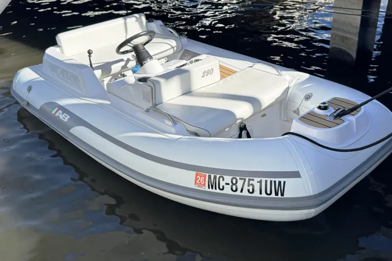  Yacht Photos Pics White inflatable boat with steering wheel, docked on calm water.