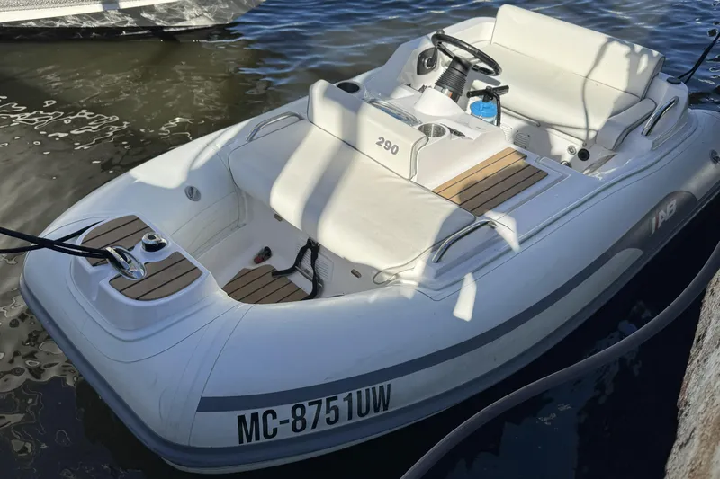  Yacht Photos Pics White inflatable boat docked on water, featuring comfortable seating and steering console.
