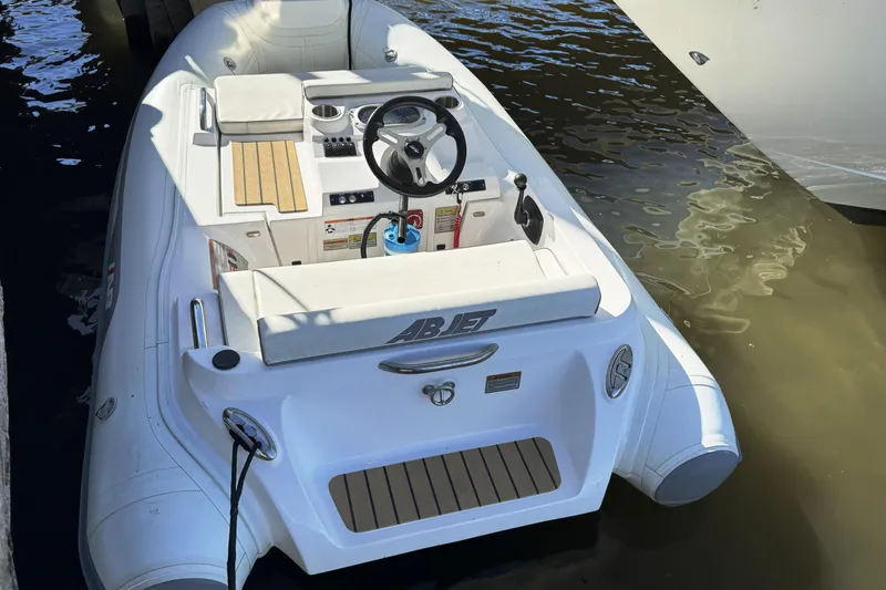  Yacht Photos Pics Small white inflatable boat docked, featuring a steering wheel and seating area.