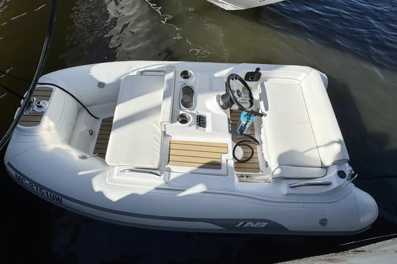  Yacht Photos Pics White inflatable boat docked on water, featuring a steering wheel and seating area.