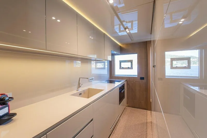 7 Seconds Yacht Photos Pics Modern yacht kitchen interior with sleek design, featuring glossy cabinets and scenic window views. Dreamline 26, 2015.