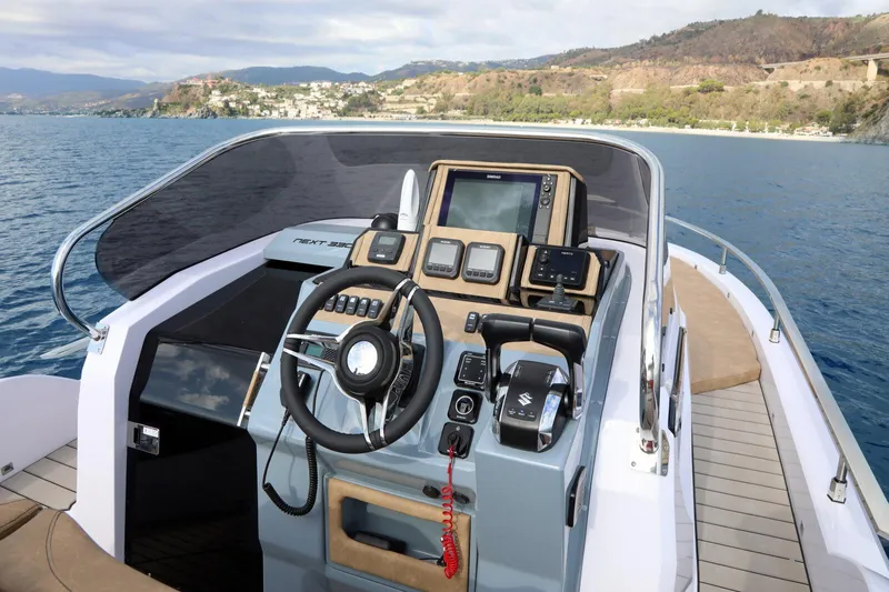  Yacht Photos Pics 2025 Ranieri NEXT 330 XL boat cockpit with modern controls and scenic coastal view.