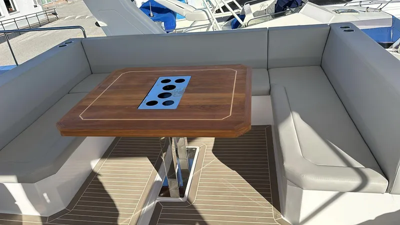 Plan C Yacht Photos Pics 2024 Leopard 53 Powercat seating area with wooden table and cushioned benches.