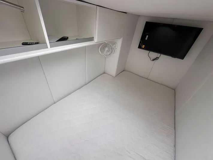 Plan C Yacht Photos Pics 2024 Leopard 53 Powercat cabin with bed, TV, and storage shelves.