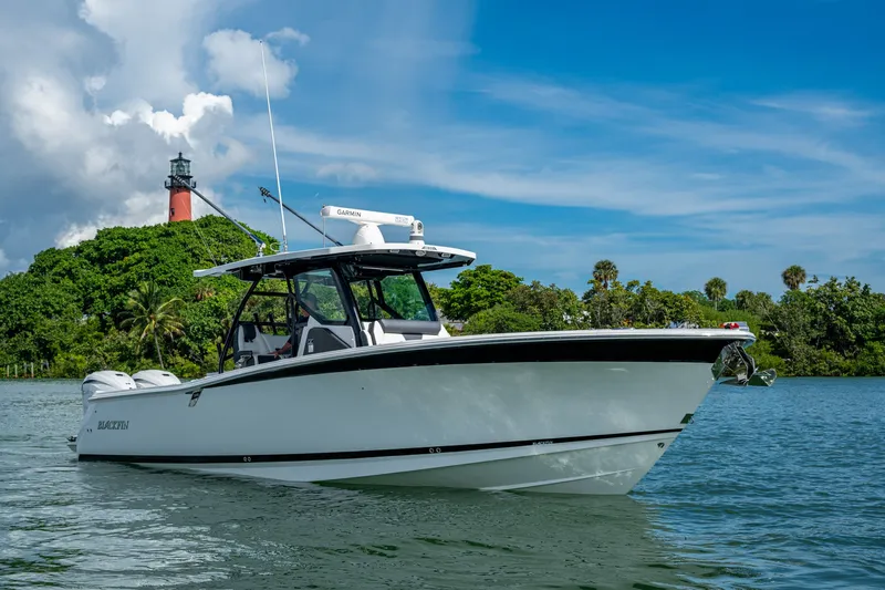 Aurora Yacht Photos Pics 2019 Blackfin 332 boat on water near lush greenery and lighthouse.