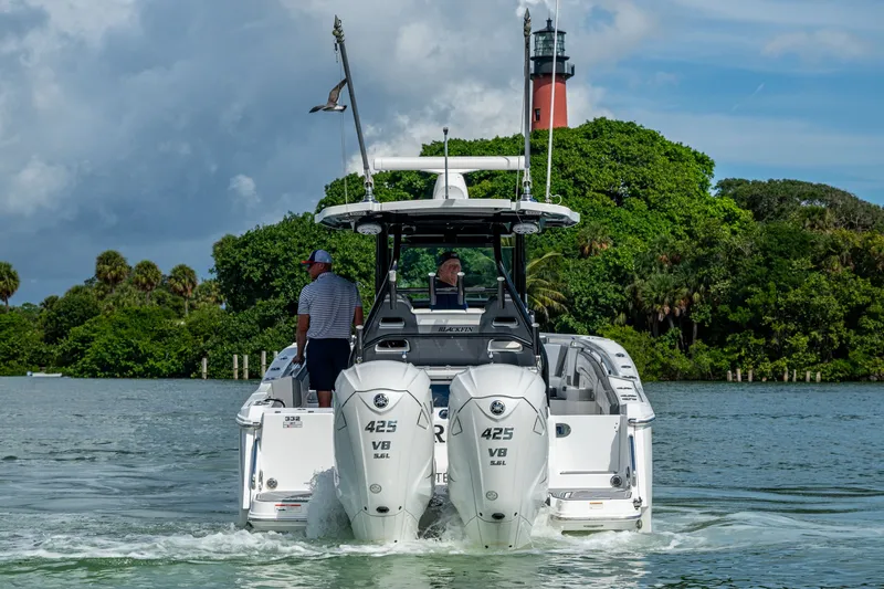 Aurora Yacht Photos Pics 2019 Blackfin 332 boat cruising near a lighthouse with lush greenery.