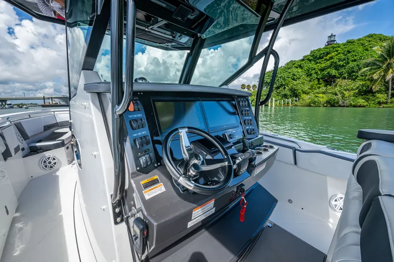 Aurora Yacht Photos Pics 2019 Blackfin 332 boat cockpit with steering wheel, control panel, and scenic water view.
