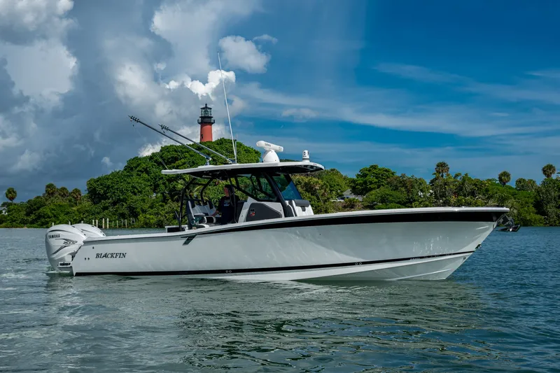 Aurora Yacht Photos Pics 2019 Blackfin 332 boat on water near lush island and lighthouse.