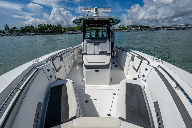 Aurora Yacht Photos Pics 2019 Blackfin 332 boat with spacious seating, docked on calm waters under a cloudy sky.