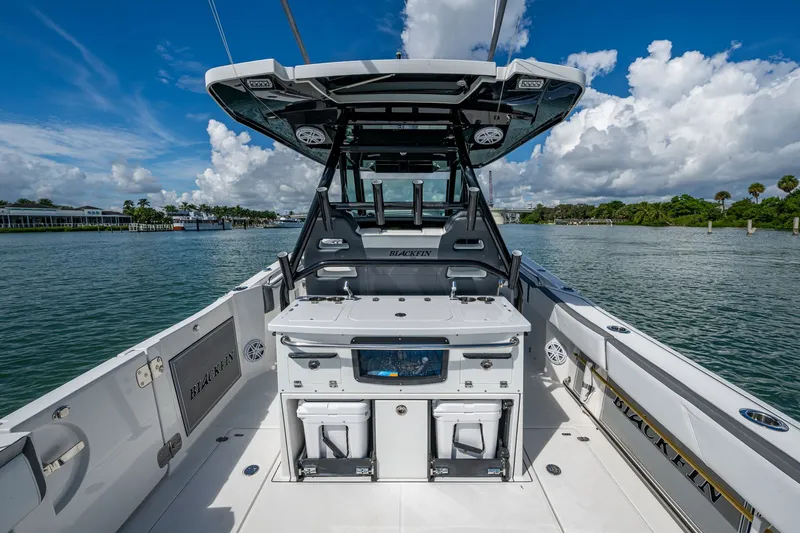 Aurora Yacht Photos Pics 2019 Blackfin 332 boat interior with fishing equipment, on a calm waterway under a blue sky.