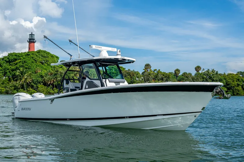 Aurora Yacht Photos Pics 2019 Blackfin 332 boat cruising near a lush island with a lighthouse.