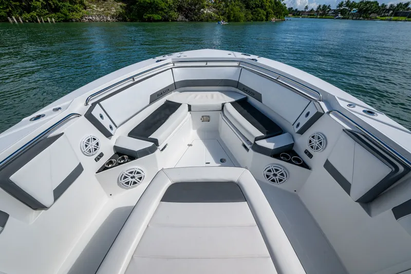 Aurora Yacht Photos Pics Luxurious 2019 Blackfin 332 boat interior with cushioned seating and speakers on a serene water backdrop.
