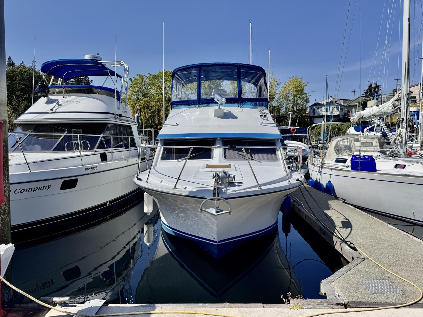 1985 Commander 30 yacht docked at marina, surrounded by other boats, under clear blue sky.