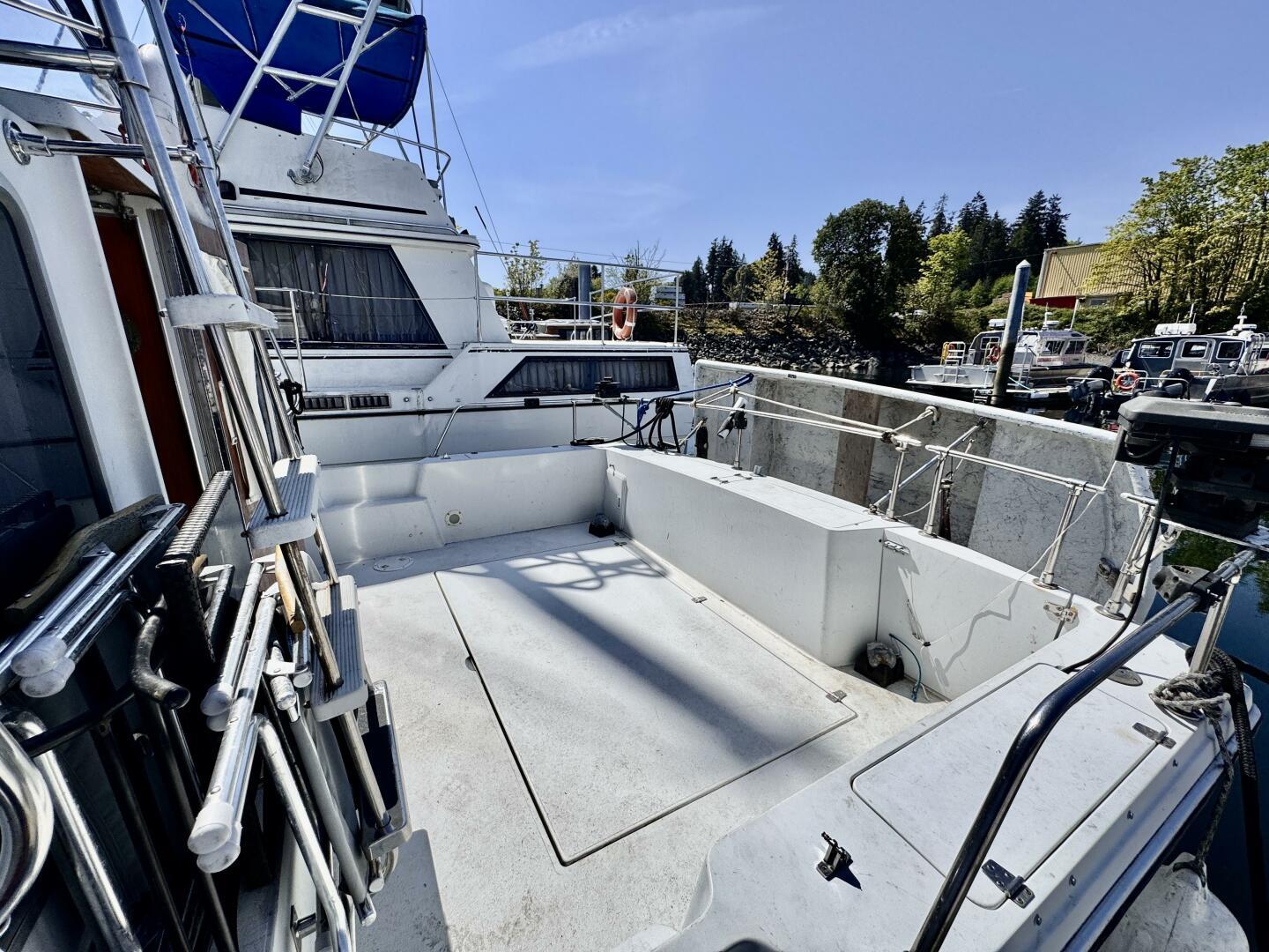 1985 Commander 30 boat deck with railing, docked at marina under clear blue sky.