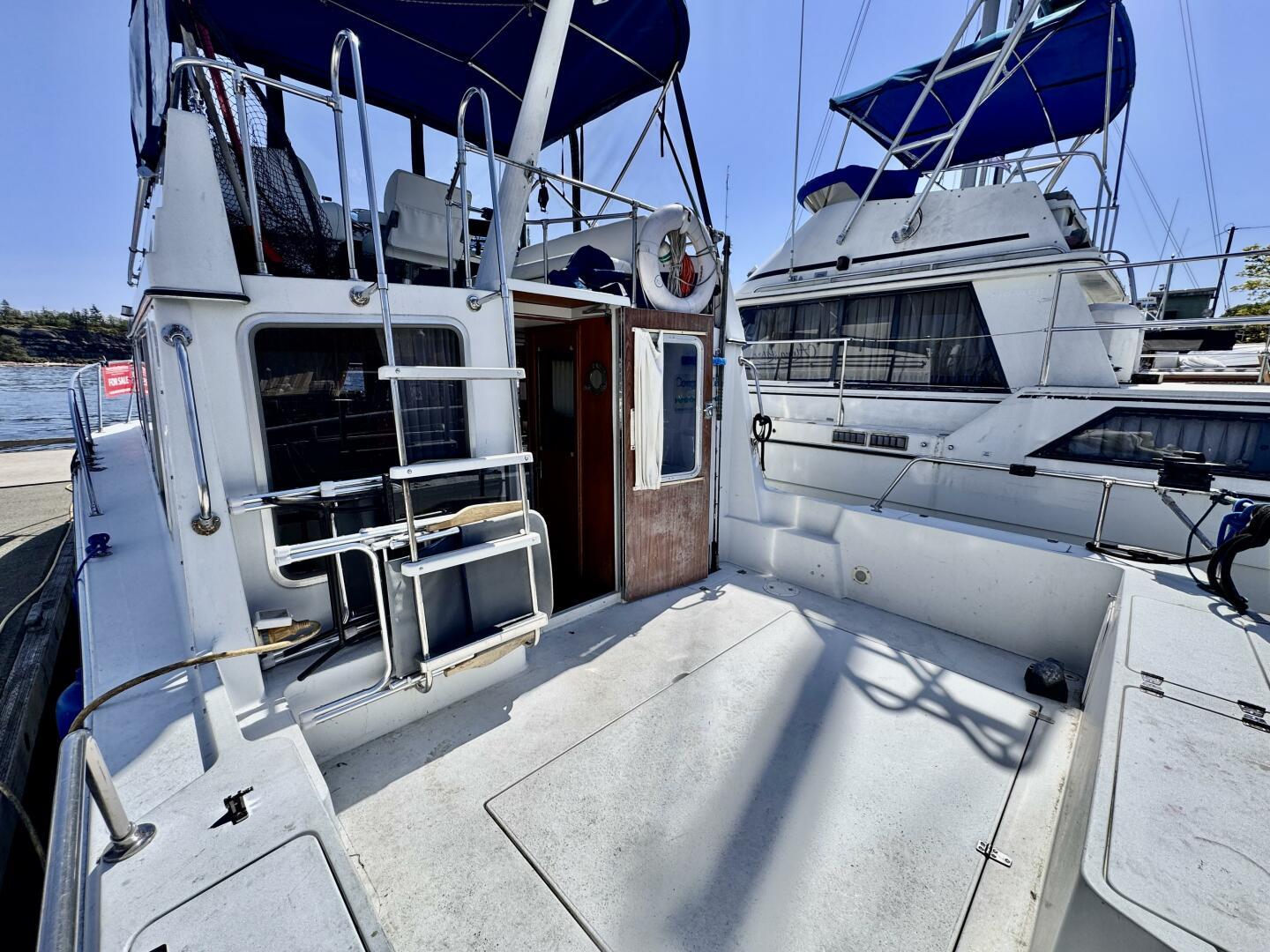 1985 Commander 30 boat docked, featuring spacious deck and blue canopy.