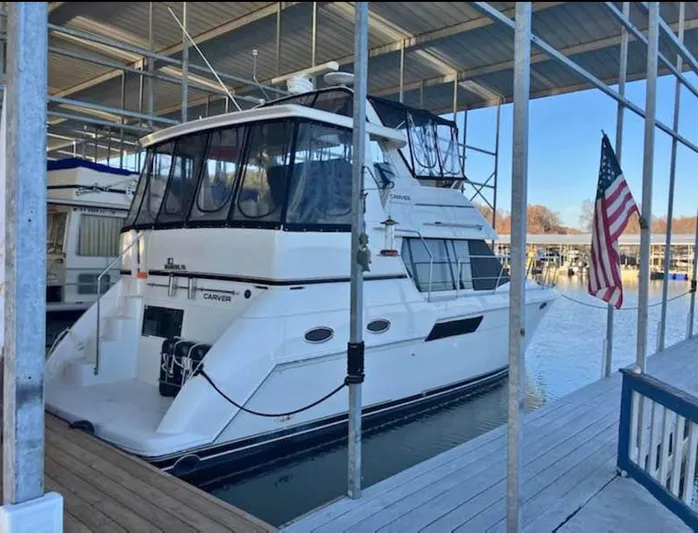  Yacht Photos Pics 2001 Carver 356 Motor Yacht docked with American flag, under covered marina.