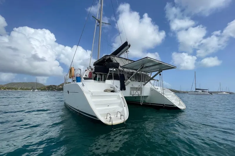 Plan B Yacht Photos Pics 2002 Lagoon 380 catamaran anchored in calm waters under a partly cloudy sky.