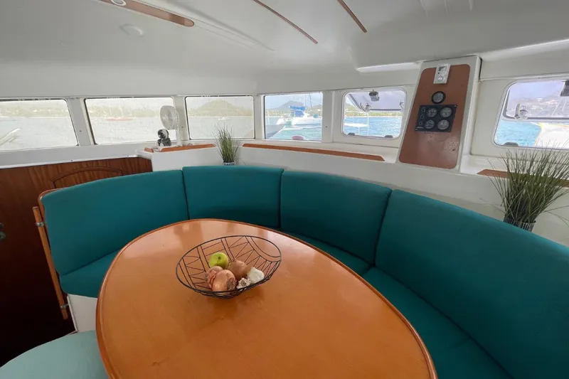 Plan B Yacht Photos Pics Interior of 2002 Lagoon 380 catamaran with teal seating and wooden table.