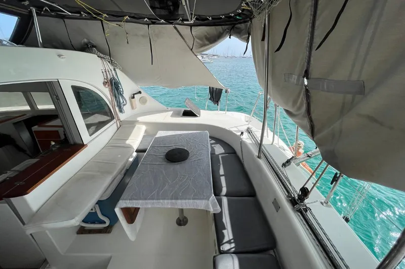 Plan B Yacht Photos Pics Lagoon 380 catamaran interior, 2002 model, featuring seating and table, overlooking turquoise water.