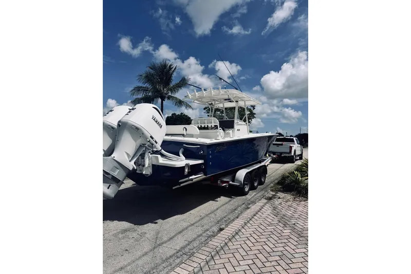  Yacht Photos Pics 2005 Jupiter 31 boat on trailer, parked near palm tree under blue sky.