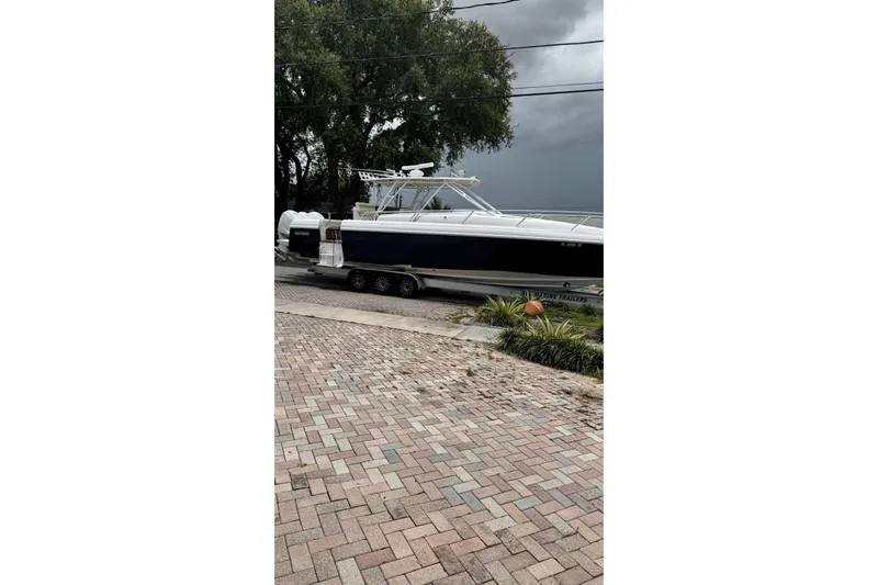  Yacht Photos Pics 2005 Jupiter 31 boat on trailer, parked on brick driveway, with overcast sky.