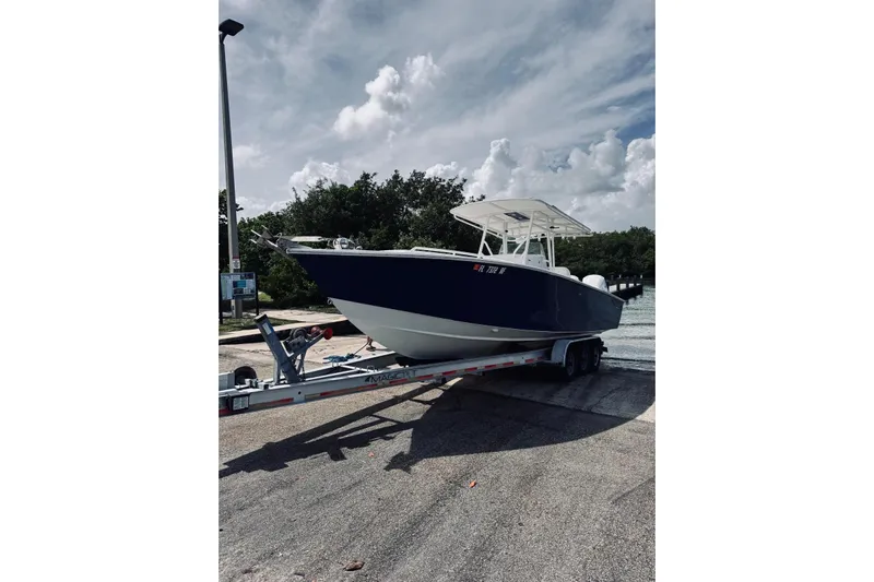  Yacht Photos Pics 2005 Jupiter 31 boat on trailer, parked near water under cloudy sky.