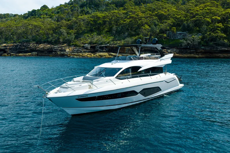 Mahalo Yacht Photos Pics 2018 Sunseeker Manhattan 66 yacht on blue water near a lush, rocky shoreline.