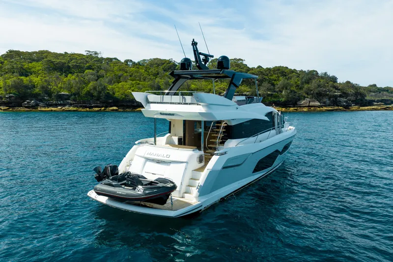 Mahalo Yacht Photos Pics 2018 Sunseeker Manhattan 66 yacht on serene water, surrounded by lush greenery.