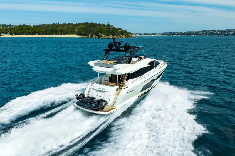 Mahalo Yacht Photos Pics 2018 Sunseeker Manhattan 66 yacht cruising on open water, scenic coastal background.