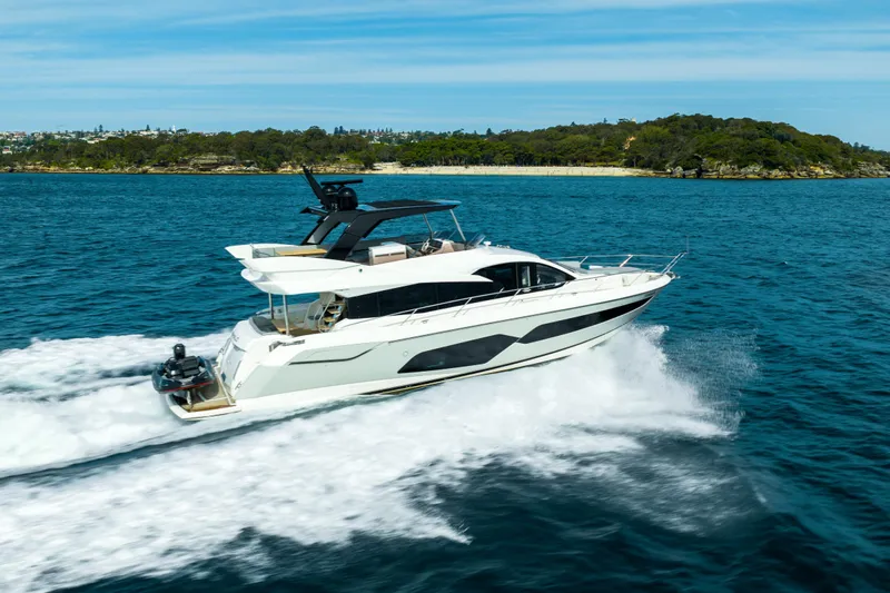 Mahalo Yacht Photos Pics 2018 Sunseeker Manhattan 66 yacht cruising on blue ocean near lush coastline.