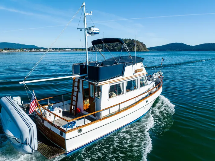 Vesper Yacht Photos Pics 1990 Grand Banks Sedan cruising on a scenic lake with mountainous backdrop.